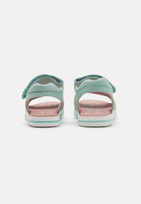 Due sandali turchesi con cinturino posteriore, tacco aperto e soletta rosa. Realizzati in materiale sintetico resistente con suole in gomma bianca.