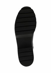Semelle de chaussure en caoutchouc noir avec une surface texturée, comportant des rainures horizontales et une forme arrondie pour une meilleure adhérence et traction.