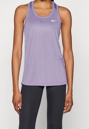Donna che indossa una canotta viola senza maniche Nike e leggings neri su uno sfondo bianco semplice.