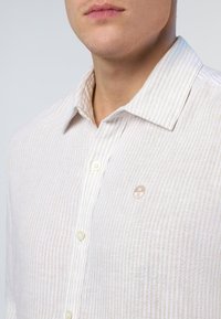 Camicia a righe di colore chiaro in tessuto di lino, con colletto button-down, piccolo logo sul petto e texture liscia.