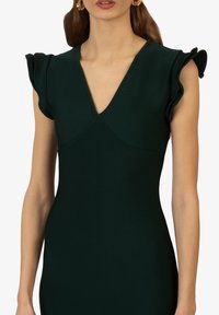 Dunkelgrünes Kleid mit tiefem V-Ausschnitt und rüschierten Kap sleeves. Hergestellt aus einem strukturierten Stoff, betont die taillierte Silhouette die Form.