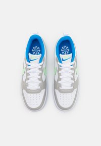Nike sneakers featuring a white leather upper, gray accents, light green swoosh, and blue padded interior with floral print insoles.