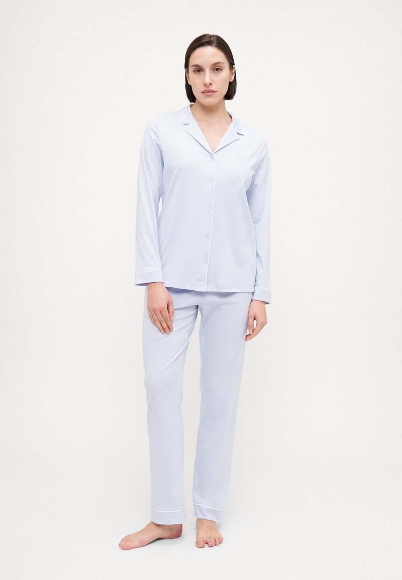 Ljusblå pyjamasset med långärmad knäppblus och löst sittande byxor, med detaljer på krage och manschetter. Mjuk, slät tyg.