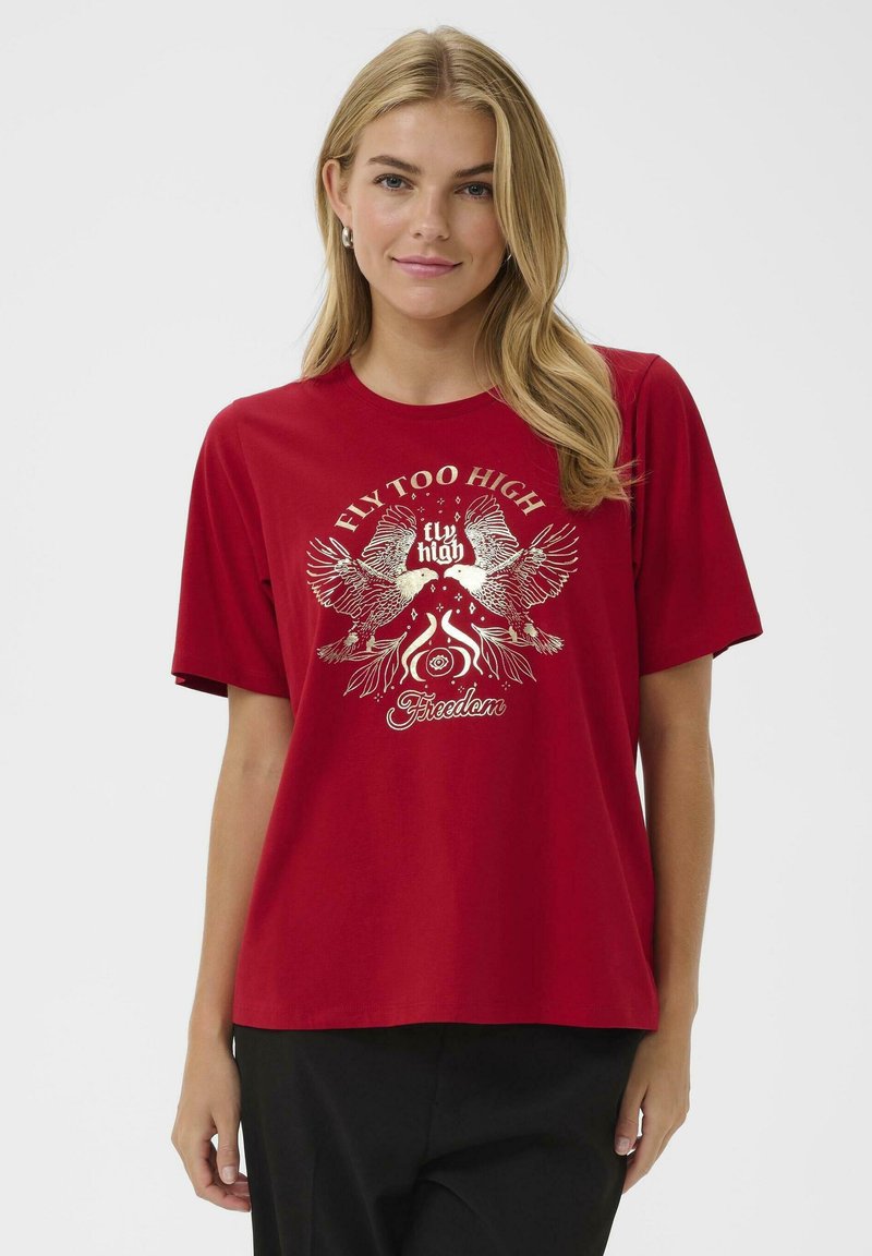 Raudona medvilninė marškinė su trumpomis rankovėmis, turinti metalinę grafikos dizainą su dviem paukščiais ir tekstu „Skristi per aukštai“ meninėmis raidėmis.