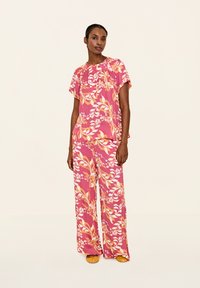 Set due pezzi stampato floreale in rosa con accenti arancioni. Top comodo con maniche corte e pantaloni a gamba larga con un motivo simile.