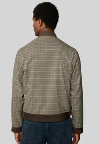 Brown checkered bomber jacket with a ribbed collar and cuffs, featuring a textured fabric and elasticized hem. Rear view with a relaxed fit.