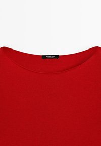 Roter Pullover mit rundem Ausschnitt, mit einem schwarzen Etikett mit der Aufschrift "Massimo Dutti" am Kragen, flach auf einem weißen Hintergrund ausgebreitet.