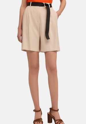 Shorts beiges en tissu léger avec des plis, une ceinture noire avec une boucle ronde, une coupe à mi-genou et des poches latérales.