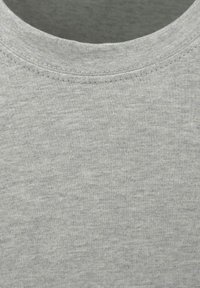 Gros plan sur un tissu de t-shirt gris, présentant un col ribbed, une texture douce et un motif de tissage uniforme, avec des coutures visibles autour de l'encolure.