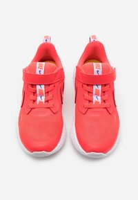 Bright red athletic shoes with a mesh upper, padded collar, and Velcro strap. Features a white sole and "Nike" branding on the tongue.