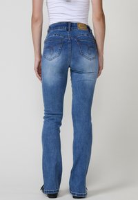 Sinivärvilised denim teksad, millel on hästi istuv siluett, eristuvad tagataskud ja tagasihoidlik kulumine. Nahkplekk vööl brändimise jaoks.