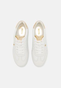 Baskets blanches en cuir et en daim, avec une surface lisse, des détails perforés et un accent doré sur le côté.