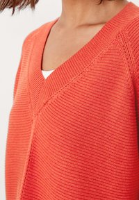 Maglione coral a coste con scollatura a V e lavorazione a maglia testurizzata. Caratterizzato da un fit rilassato con leggera elasticità e cuciture strutturate.