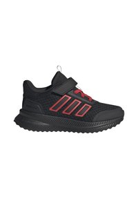 Zapatillas deportivas negras con parte superior de malla, acentos rojos y una correa de gancho y bucle. Suela gruesa y texturizada con un patrón en zigzag para mayor agarre.