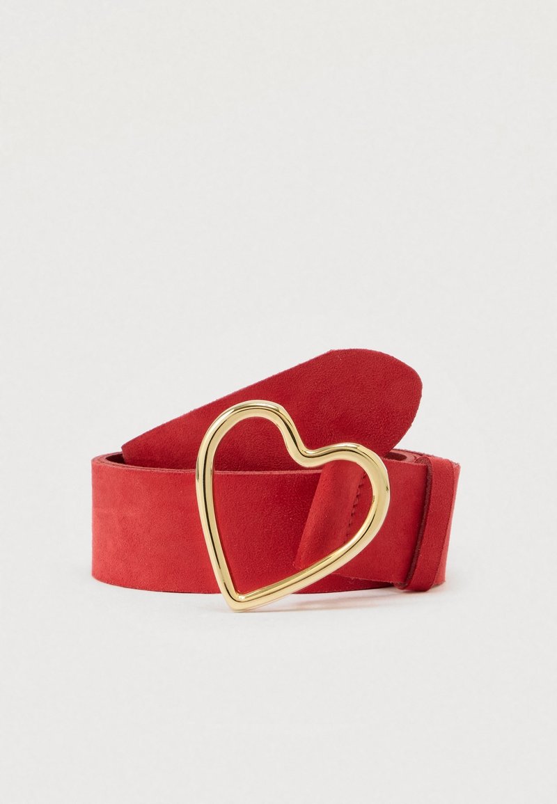Ceinture en daim rouge roulée avec une boucle dorée en forme de cœur sur un fond clair uni.