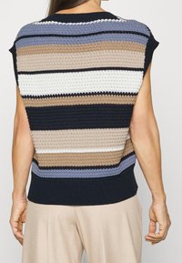 Stickad ärmlös topp med horisontella ränder i marinblått, beige, kräm och blått. Har en ribbad nederkant och en avslappnad passform. Texturerad tyg.