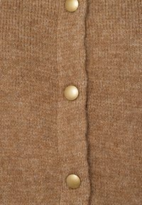 Brauner gestrickter Cardigan mit einer weichen Textur, ausgestattet mit goldfarbenen Knöpfen und einer zentralen Öffnung. Der Stoff wirkt warm und gemütlich.