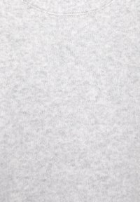 Svetlosivá textúra tkaniny s jemným vzorom pletenia a jemnými variáciami v odtieňoch a hustote vlákien.