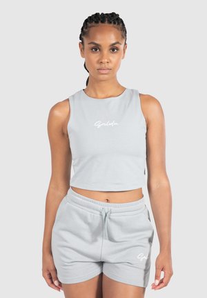 Hellgrauer Cropped-Top mit rundem Hals und weißer Schrift, kombiniert mit passenden Shorts mit elastischem Bund und seitlichen Taschen.
