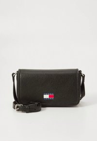 Black textured leather crossbody bag with a flap and adjustable strap. Features a red and blue logo patch on the front.