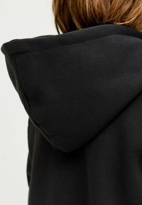 Felpa nera con cappuccio dal tessuto morbido. Presenta un cappuccio leggermente oversize e un design pulito e minimalista.