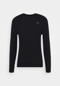 Svart tröja i stickad tyg, med långa ärmar, rundad halsringning och en liten, broderad logotyp på vänster bröst.