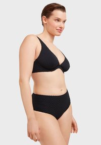 Set bikini nero con tessuto testurizzato, coppe sagomate, spalline regolabili e slip a vita alta con un elastico liscio in vita.