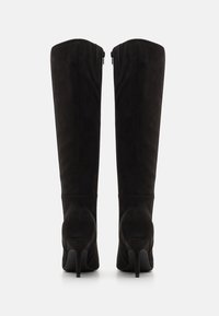 Bottes noires au-dessus du genou en daim souple, avec un talon aiguille haut, fermeture éclair et texture lisse sur la tige.