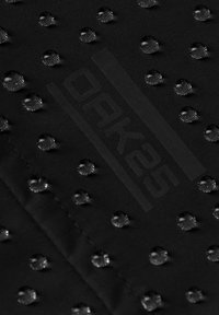 Tela negra con puntos texturizados elevados espaciados uniformemente y la palabra "Orkash" impresa en el centro.