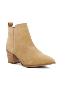 Tan suede ankle boot with a pointed toe, side elastic panels, and a stacked wooden heel. Smooth texture and minimalistic design.