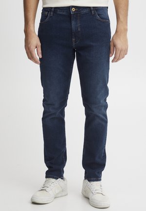 Mørkeblå denimjeans med slank passform, fem lommer og kontraststing. Passer godt sammen med hvite joggesko for hverdagsbruk.
