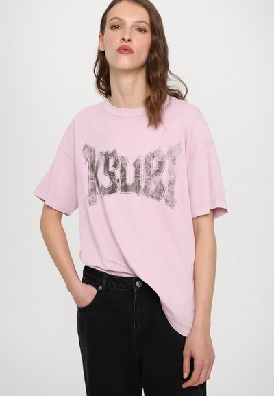 Ljusrosa oversized t-shirt med en svart grafisk tryck som står "Ksubi." Korta ärmar och rundad halsringning, tillsammans med svarta byxor.