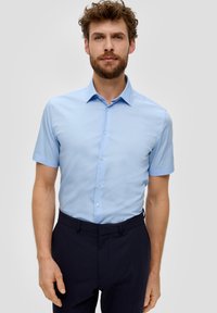Hellblaues kurzärmeliges Hemd mit Knopfleiste und spitzem Kragen, glatte Textur und subtilen Glanz. Getragen mit dunklen Hosen.