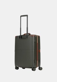 Valigia rigida verde scuro con texture a righe, dettagli in pelle marrone, manico estensibile e quattro ruote nere per la mobilità.
