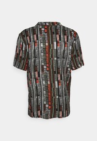 Lyhythihainen paita, jossa on monivärinen pystysuora raitakuosi mustassa, punaisessa, vihreässä ja valkoisessa. Kevyt kangas ja rento istuvuus.