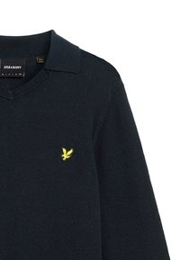 Maglione lavorato a maglia di un blu navy scuro con un colletto a V e un logo di aquila giallo sul petto. Realizzato in materiale morbido con colletto a coste.