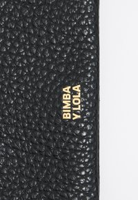 Juodas textūruotas odinis piniginė su įspaustu raštu ir auksiniu logotipu "BIMBA Y LOLA" priekyje.