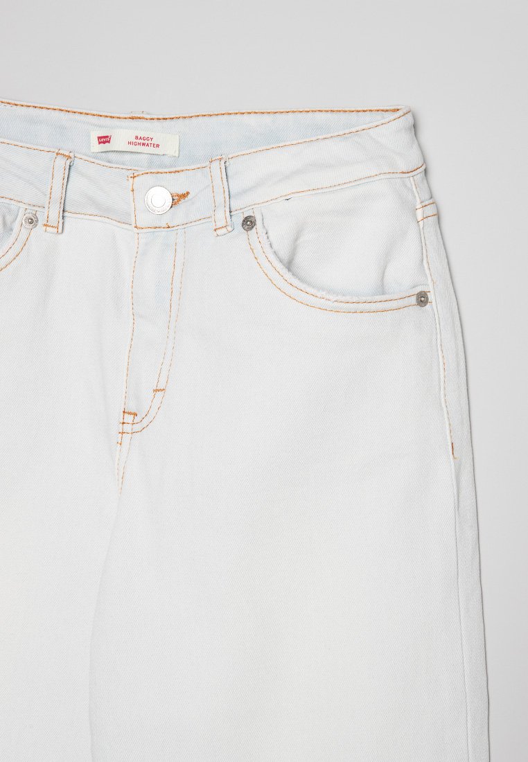Jeans in denim bianco con cuciture arancioni a contrasto; presentano un classico design a cinque tasche e una chiusura con bottone in vita.