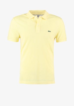 Gelbes Poloshirt aus Baumwolle mit klassischem Kragen, kurzen Ärmeln und einem grünen Logo auf der linken Brust, das ein strukturiertes Muster aufweist.