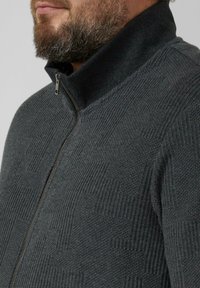 Dark gray zip-up sweater with a high collar, featuring textured knit patterns and a smooth zipper. Made from a soft, thick fabric.