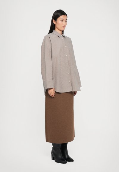 Long-sleeve striped shirt in light brown and beige, paired with a fitted brown knit skirt and black heeled boots. Simplicity in design.