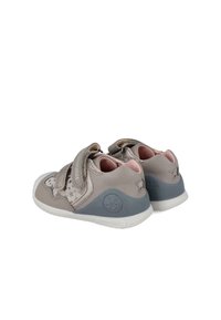 Zapatos infantiles de color gris claro con un patrón de estrellas, dos tiras de Velcro, interior suave de color rosa y un acabado de goma gris en el talón.