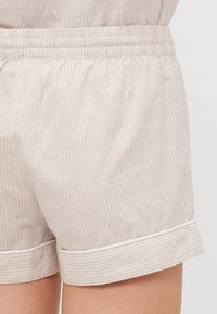 Licht beige katoen shorts met verticale witte strepen, voorzien van een elastische tailleband en witte rand aan de onderkant.