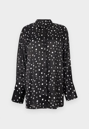 Schwarze Satinhoch mit weißen Polka-Dots, langen Ärmeln und einem Kragen. Mit Knopfverschluss und lockerer Passform.