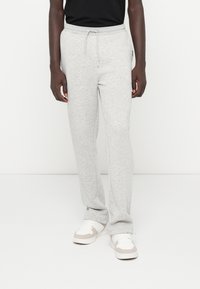 Graue Sweatpants aus weichem Stoff, mit einem elastischen Bund und einem Kordelzug, geraden Beinen und einer dezenten Textur.