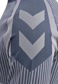 Gelaagd sportshirt in blauw en grijs met gestreepte patronen. Heeft opvallende chevron-ontwerpen in contrasterende stof.