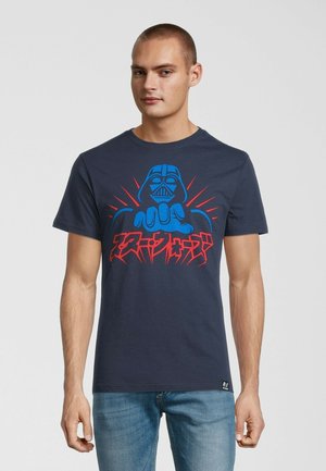 Mørkeblå bomulds t-shirt med et grafisk motiv af en karakter med røde og blå detaljer samt fed tekst nedenfor. Kortærmet og med rund halsudskæring.