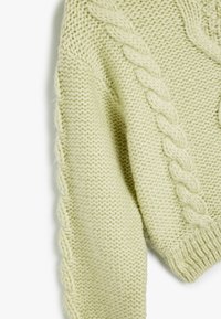 Maglione lavorato a maglia in verde menta, con cuciture a treccia testurizzate lungo le cuciture e un orlo a coste, realizzato in filato morbido e soffice.