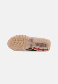 Shoe sole with a textured rubber pattern, mainly translucent pink with red accents, featuring circular details and a tread design for traction.