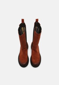 Brązowe zamszowe botki za kostkę z czarnymi bokami, z uchwytem i wielokolorowym, paskowanym wnętrzem. Okrąły czubek i płaska, czarna gumowa podeszwa.